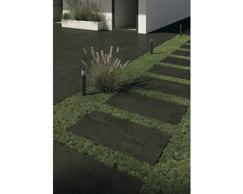 Gehwegplatten aus Stein bilden einen Pfad durch einen Garten, beleuchtet von Gartenleuchten.