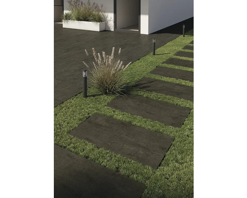 Außenaufnahme mit Terrassenplatten, Rasen und Außenleuchten.