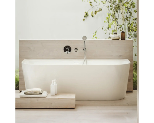 Freistehende Badewanne mit Armatur und Handbrause in einem hellen Badezimmer.