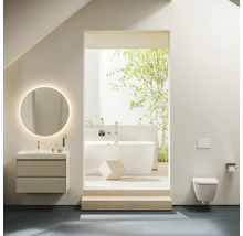 Badezimmer mit Waschtisch, beleuchtetem Spiegel, Badewanne und Wandtoilette