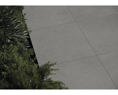 Verlegte Terrassenplatten neben Grünpflanzen.