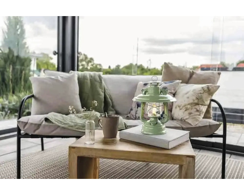 Dekorative Wohnszene mit Sofa, Kissen, Decke, Tisch, Lampe, Tasse und Vase mit Blumen.