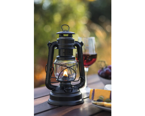 Schwarze Petroleumlampe auf einem Holztisch mit Snacks und Getränken