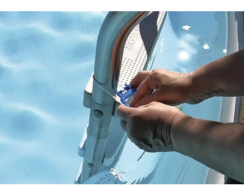 Eine Person befestigt ein blaues Thermometer mit Kabel an einer Schwimmbadleiter