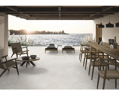 Große Terrasse mit Fliesenboden, Liegestühlen, Tisch und Stühlen mit Meerblick.