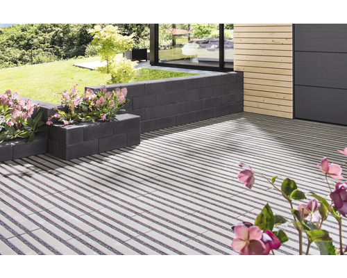 Terrasse mit Pflastersteinen und Mauer mit Blumen