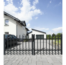 Toranlage aus Metall vor einem Wohnhaus mit gepflasterter Einfahrt.