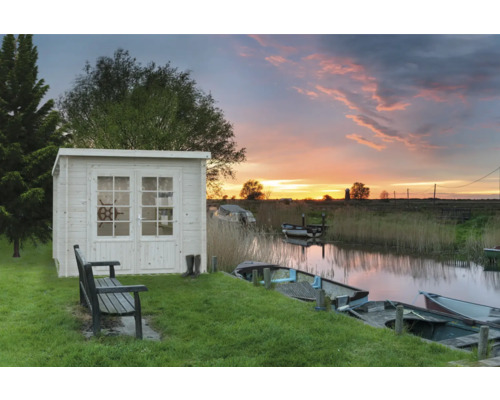 Garten mit Holzgartenhaus, Sitzbank und Blick auf einen Kanal bei Sonnenuntergang.