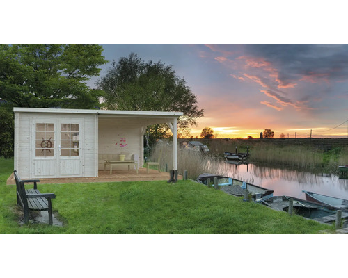 Holzgartenhaus mit überdachter Veranda und Blick auf einen Fluss mit Booten bei Sonnenuntergang.