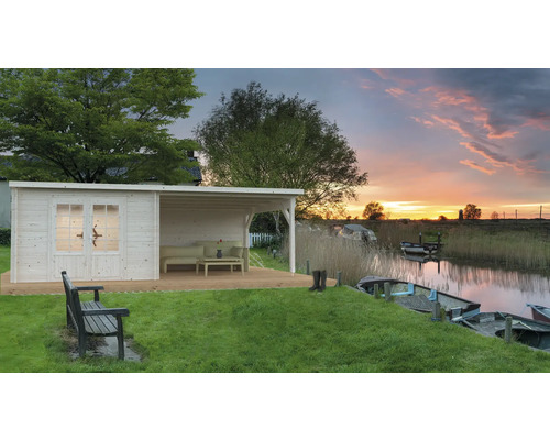 Holzgartenhaus mit Terrasse und Blick auf einen See bei Sonnenuntergang.