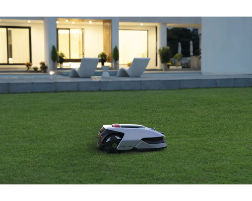 Rasenmähroboter auf Rasenfläche vor einem Haus