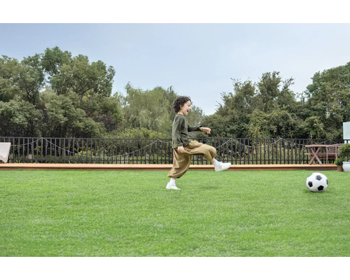Junge spielt Fußball auf Kunstrasen im Garten.