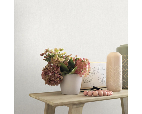 Nahaufnahme einer strukturierten Tapete mit Blumenarrangement und Dekorationsgegenständen auf einem Tisch