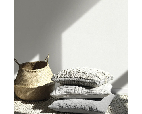 Dekorative Szene mit Korb und gestapelten Kissen auf einem Teppich.