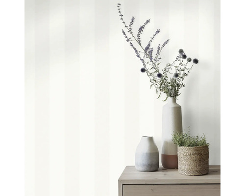 Dekorative Szene mit gestreifter Tapete, Blumenvasen und Pflanze im Korb auf einem Holzschrank