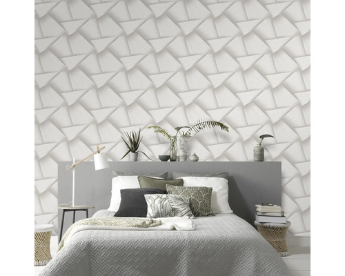 Schlafzimmer mit Bett vor einer Wand mit dreidimensionaler geometrischer Tapete