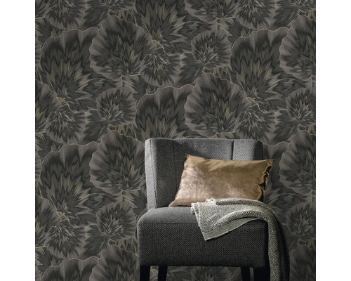 Nahaufnahme eines Zimmers mit einer grauen Sesselgarnitur vor einer floralen Tapete