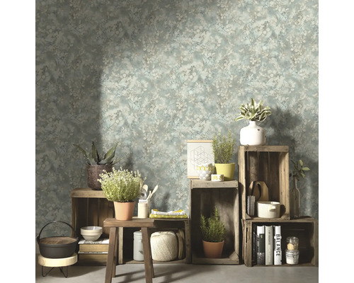 Wohnraum mit floral gemusterter Tapete, Holzkisten und dekorativen Gegenständen.