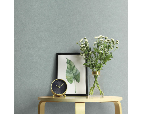 Nahaufnahme einer Zimmerdekoration mit Tischuhr, gerahmtem Bild und Blumenvase vor einer hellen Wand