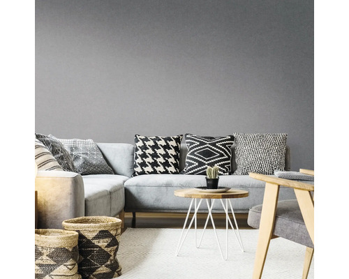 Wohnzimmer mit grauem Ecksofa, gemusterten Kissen, Holztisch und geflochtenen Körben auf einem Teppich