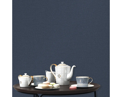 Teeservice und Makronen auf einem Tisch vor einer blauen Wand