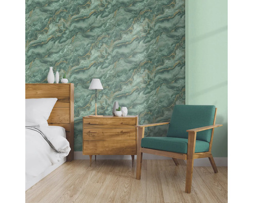 Schlafzimmer mit Bett, Nachttisch und Sessel vor einer Wand mit Marmortapete.