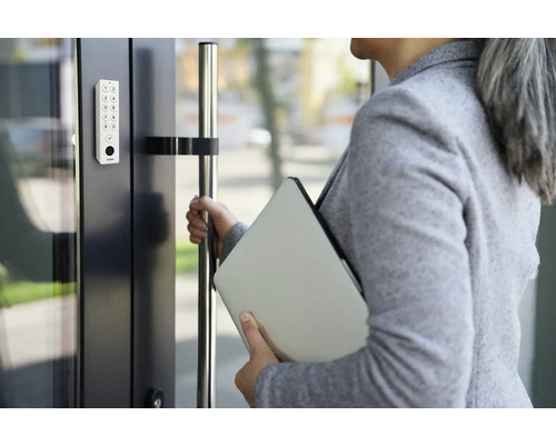 Frau öffnet Tür mit digitalem Zahlenschloss