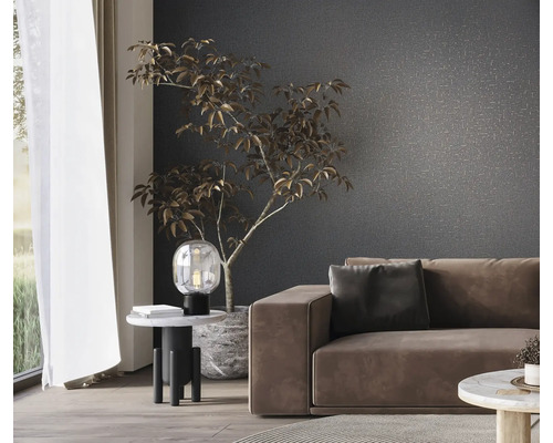 Wohnzimmer mit Sofa, Tischlampe und Zimmerpflanze vor einer gemusterten Wand