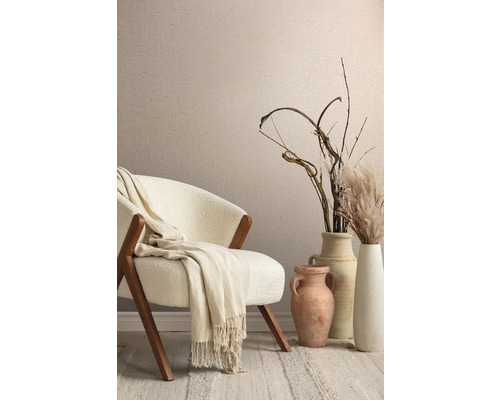 Dekoratives Interieur mit Sessel, Decke, Vasen und Ziergräsern vor einer Wand mit Textiltapete.