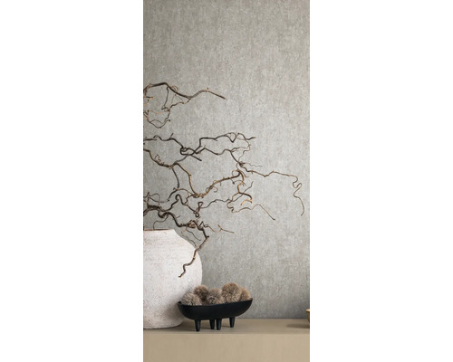 Dekorative Äste in Vase vor einer strukturierten Wand