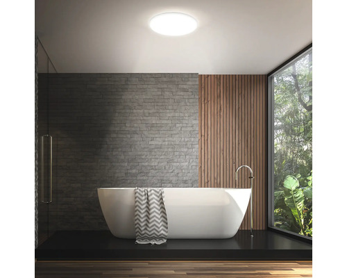 Helles Badezimmer mit Badewanne, Akzentwand und runder Deckenleuchte