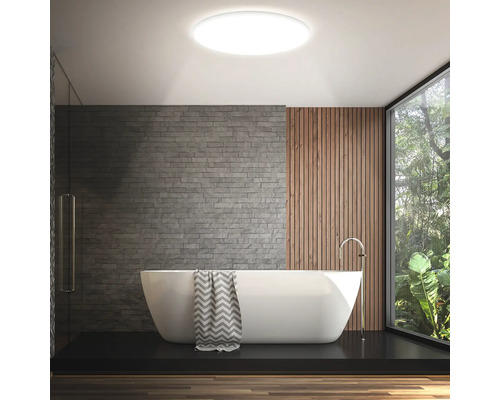 Badezimmer mit Badewanne, Steinwand, Holzvertäfelung und runder Deckenleuchte