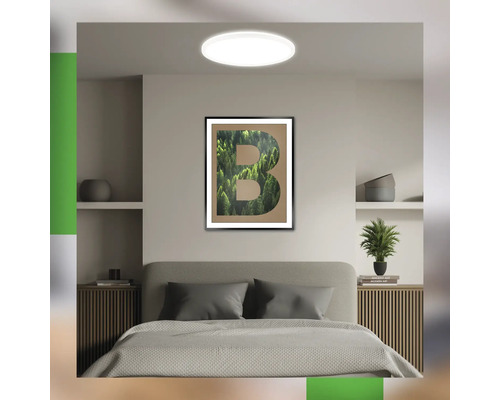 Schlafzimmer mit Deckenleuchte und gerahmtem Buchstaben-Kunstdruck