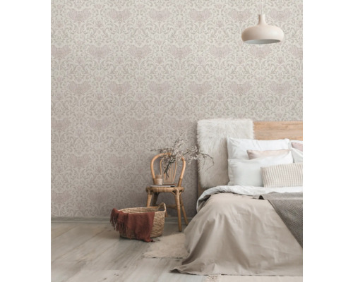 Schlafzimmer mit gemusterter Tapete, Bett und Korbsessel