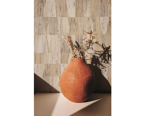 Dekorative Vase mit Trockenblumen auf einem Tisch vor einer strukturierten Wand