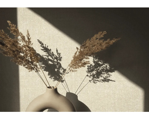 Dekorative Vase mit getrocknetem Schilfgras vor einer Wand