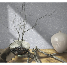 Dekorative Anordnung mit Vase, Ästen und Dekosteinen auf einem Holztisch vor einer strukturierten Wand.