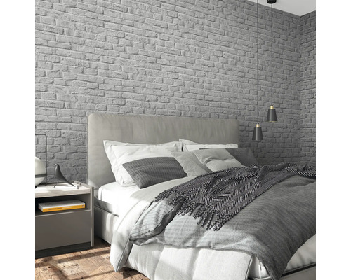 Schlafzimmer mit Bett, Nachttisch und grauer Backstein Tapete