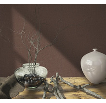 Dekoratives Stillleben mit Vase, Zweigen und Stoff auf einem Holztisch vor einer einfarbigen Wand