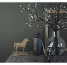 Dekoratives Stillleben mit Holzpferd, Vase, Pflanzen und Bildern auf einem Tisch.