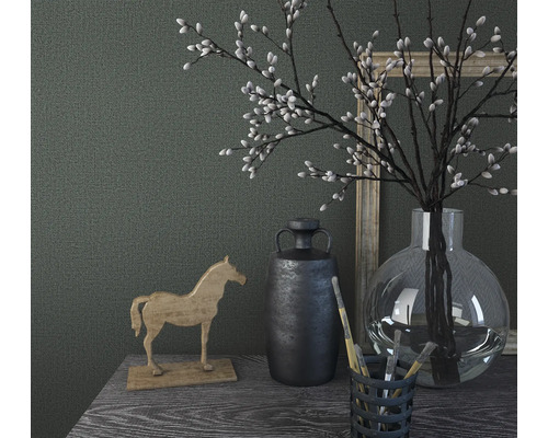 Dekoratives Stillleben mit Holzpferd, Vase, Pflanzen und Bildern auf einem Tisch.