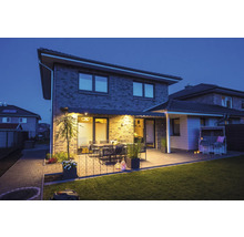 Haus mit Terrasse, Gartenmöbeln und Rasenmähroboter bei Dämmerung