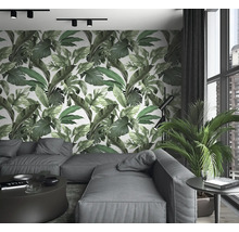 Wohnzimmer mit Sofa, Tisch, Zimmerpflanze und Wandtapete mit Blätterdruck