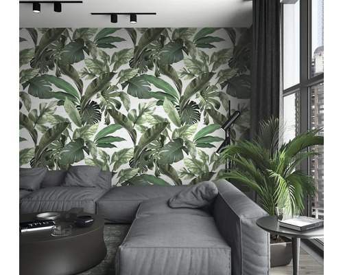 Wohnzimmer mit Sofa, Tisch, Zimmerpflanze und Wandtapete mit Blätterdruck