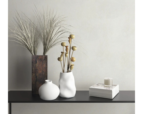 Dekorative Szene mit Vasen, Zierpflanzen, Kerze und Zeitschriften auf einem Tisch.