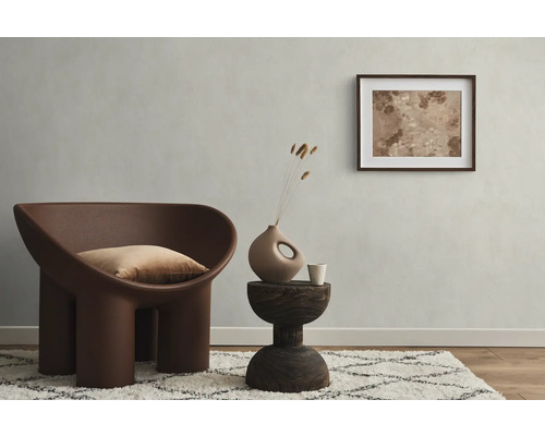 Wohnzimmer mit Sessel, Kissen, Beistelltisch, Dekoration und gerahmtem Bild