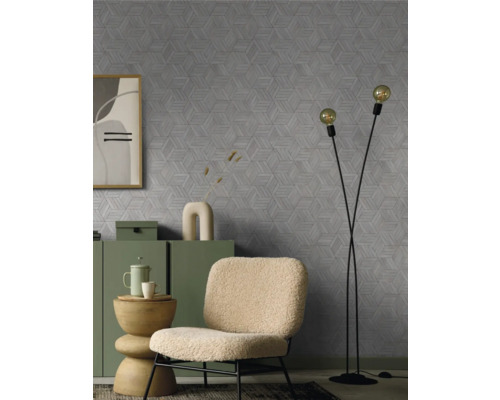 Wohnzimmer mit einem Sessel, Stehlampe und einer Kommode vor einer Wand mit einem geometrischen Muster.