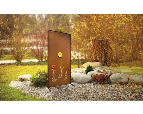 Gartenszene mit braunem Sichtschutz mit Blumendesign auf Kies