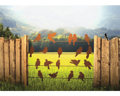 Dekorative Vogel-Silhouetten auf einem Zaun vor einer grünen Landschaft.
