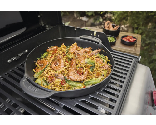 Wokgericht mit Garnelen und Gemüse auf einem Grill zubereitet.